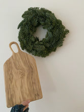 Load image into Gallery viewer, UNe planche en bois d'olivier brut présentée avec une couronne de Noel naturelle faite par millimetres.be