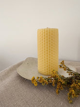 Afbeelding in Gallery-weergave laden, Coupelle Feuille en grès clair moucheté, accueillant une bougie jaune à texture alvéolée, sur un tissu beige avec des fleurs séchées. 
