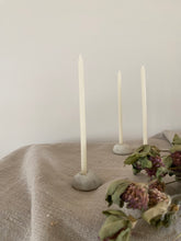 Load image into Gallery viewer,  Bougeoirs Petit Poucet en grès clair avec de fines bougies blanches, disposés sur un tissu beige à côté de fleurs séchées.
